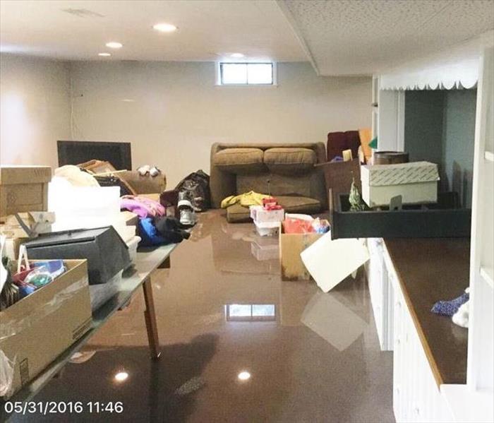 Basement with couch, cabinets, boxes and other contents surround by water