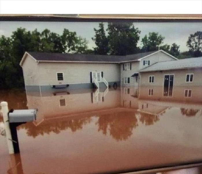 Building and mailbox surrounded by muddy flood water
