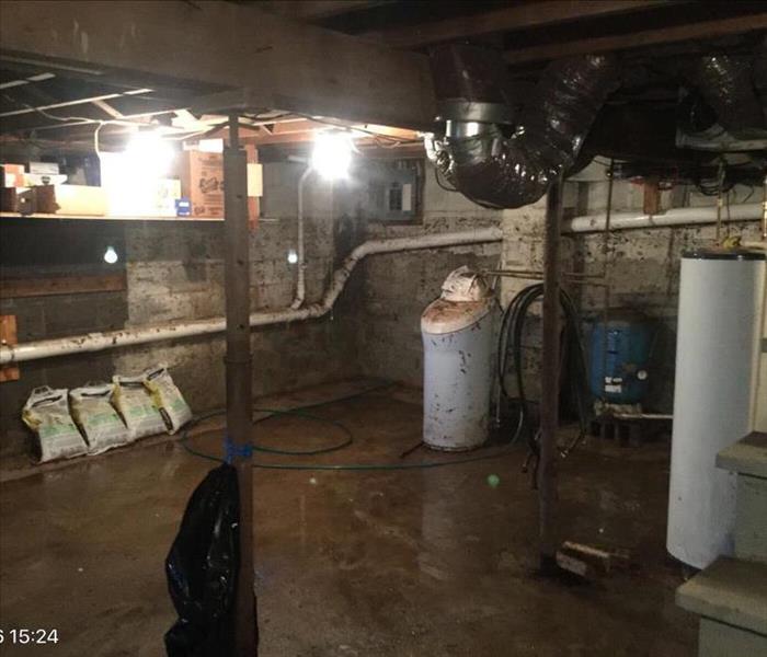 Concrete basement with muddy flood water marks up the wall almost the whole way