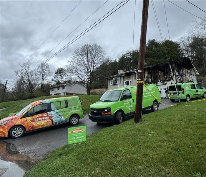 several vehicles in driveway of house with fire damage